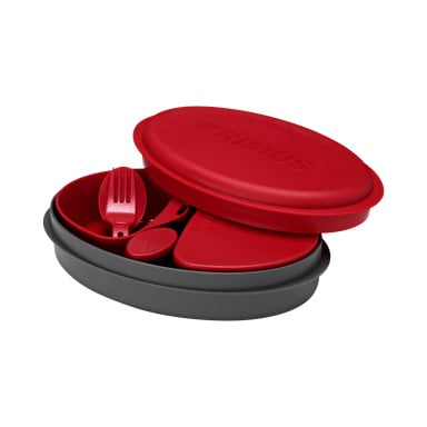 Ett åttadelat Primus Camping Set i rött och grått visas med ett delvis öppet lock som visar den präglade Primus-logotypen. Inuti finns en matchande röd spork, en liten röd behållare och en triangulär röd accessoar.