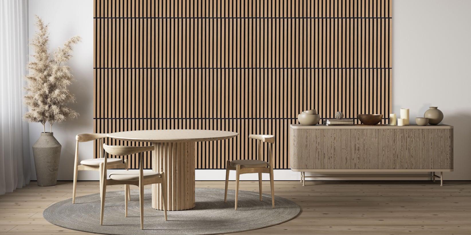 En minimalistisk matsal med ett runt träbord, fyra matchande stolar, en stor skänk, torkat pampasgräs i en hög vas, neutrala inredningsdetaljer, en rund matta och en accentvägg med träribbor.