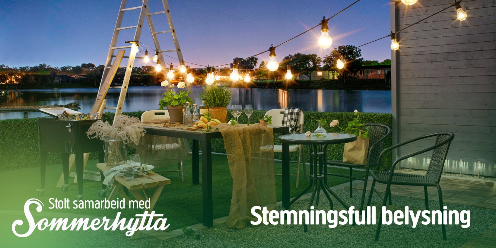 En uteservering ved innsjøen i skumringen har lyskæder på en stige og et dekket bord. Tekst: Stolt samarbeid med Sommerhytta: Stolt samarbeid med Sommerhytta. Stemningsfull belysning.