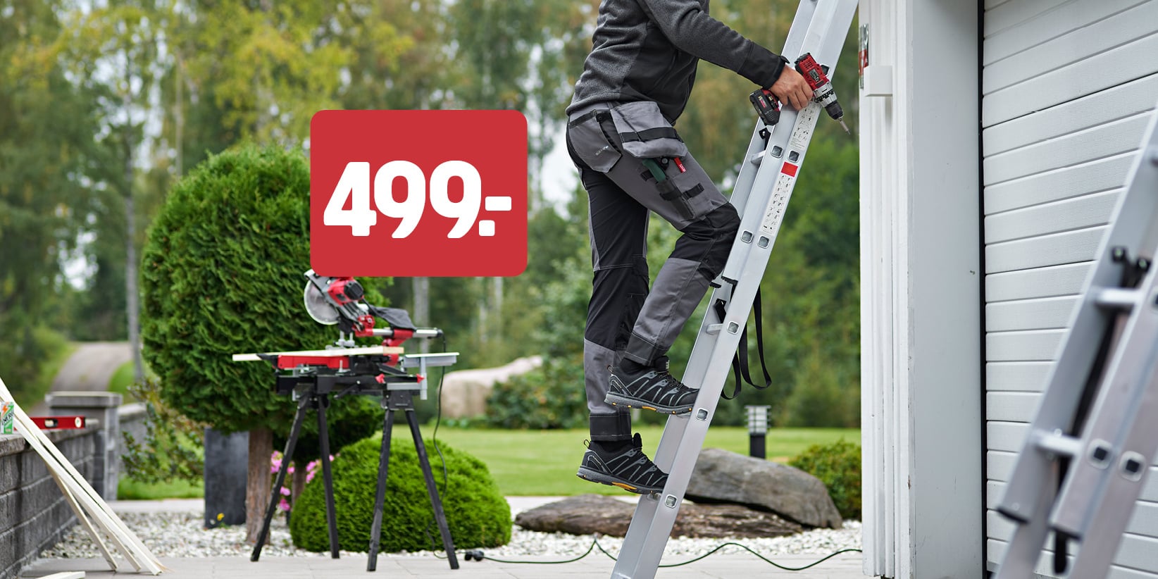 Någon klättrar uppför en metallstege som står lutad mot en vit byggnad. I närheten syns en röd skylt med texten ”499-”. I bakgrunden syns en bordssåg och lite grönska.